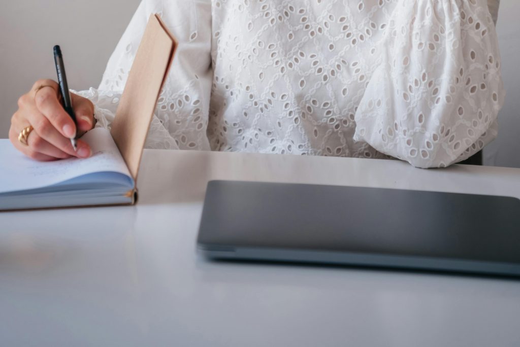 Professionnelle écrivant dans un carnet à son bureau, illustrant une démarche de clarification et de réalignement professionnel.